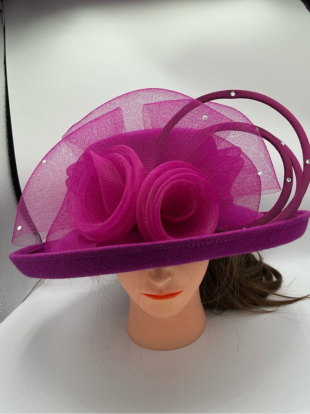 Magenta fascinator hat with large mesh roses and rhinestone-accented loops